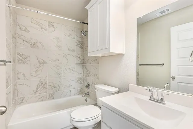 a bathroom with a bathtub shower sink vanity and toilet