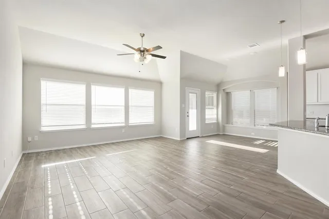 a view of an empty room with window and wooden floor