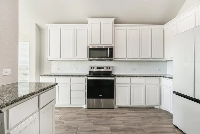 a kitchen with granite countertop white cabinets and black appliances