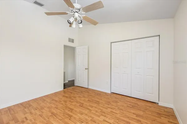an empty room with wooden floor ceiling fan and windows