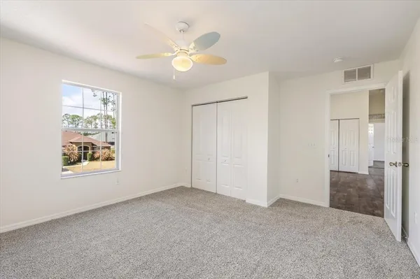 a view of an empty room and chandelier fan
