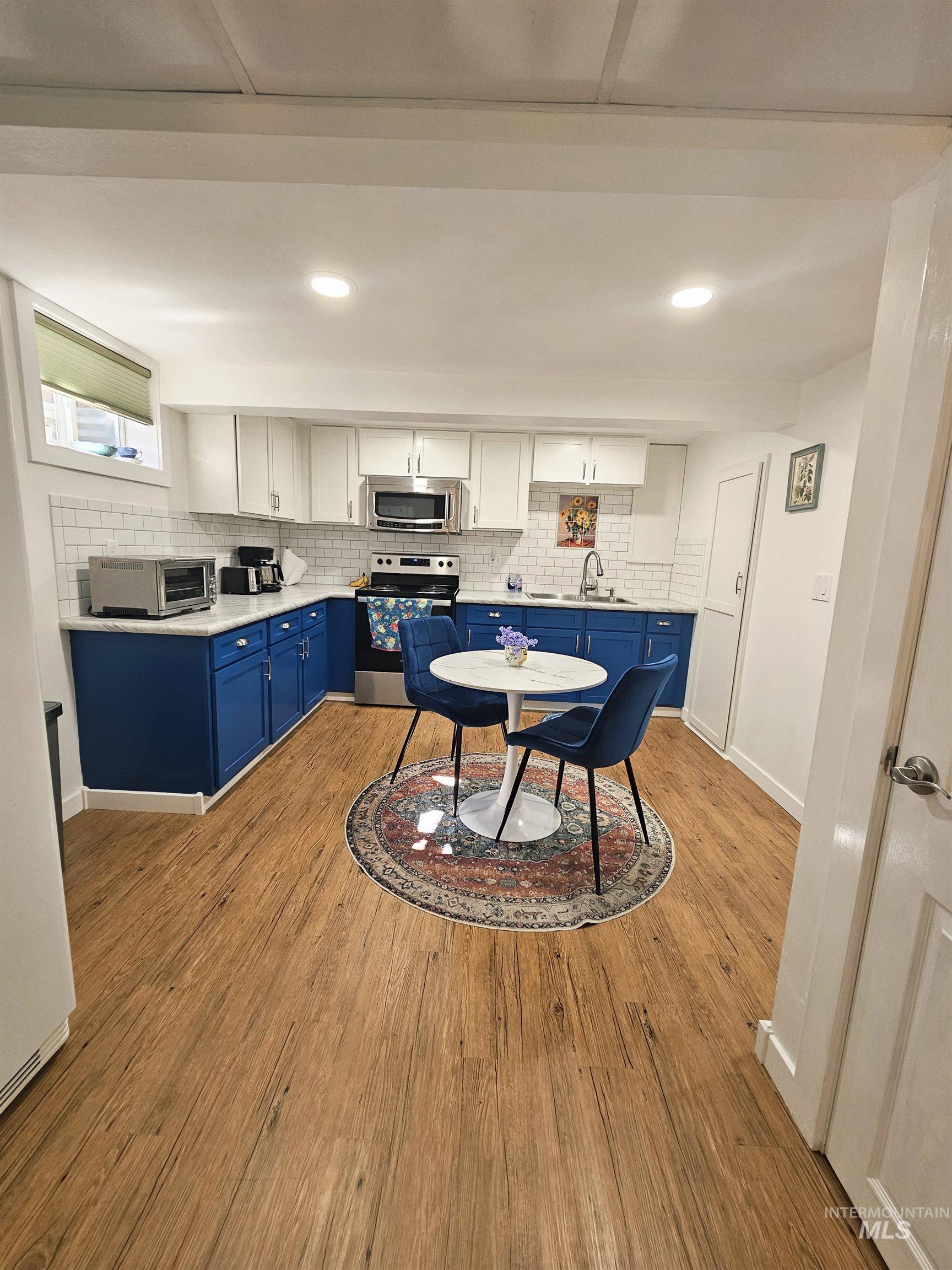 712 3rd Street Lewiston, ID 83501 - Photo 21 of 30 Two tone kitchen featuring stainless steel appliances, light wood-style floors, two tone cabinets, tasteful backsplash, and recessed lighting