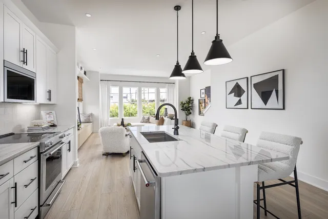 a open kitchen with stainless steel appliances granite countertop a kitchen island a stove a sink a dining table and chairs with wooden floor