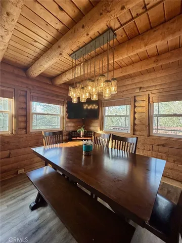 a kitchen with stainless steel appliances granite countertop a sink a table chairs and a wooden floor