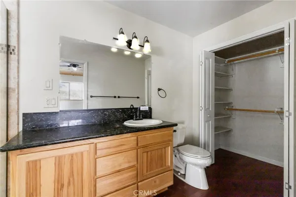 a bathroom with a granite countertop sink a toilet a mirror and shower