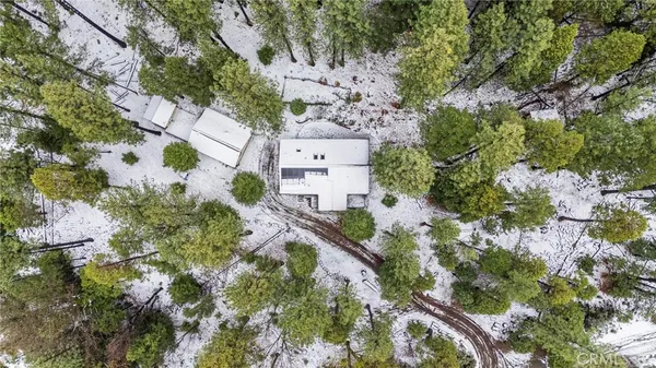 an aerial view of residential house with outdoor space and trees all around