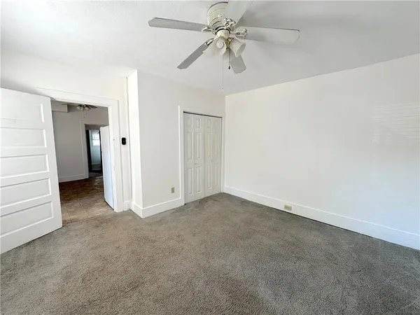 an empty room with closet and a ceiling fan