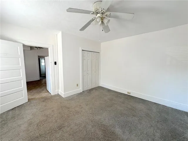 an empty room with closet and a ceiling fan