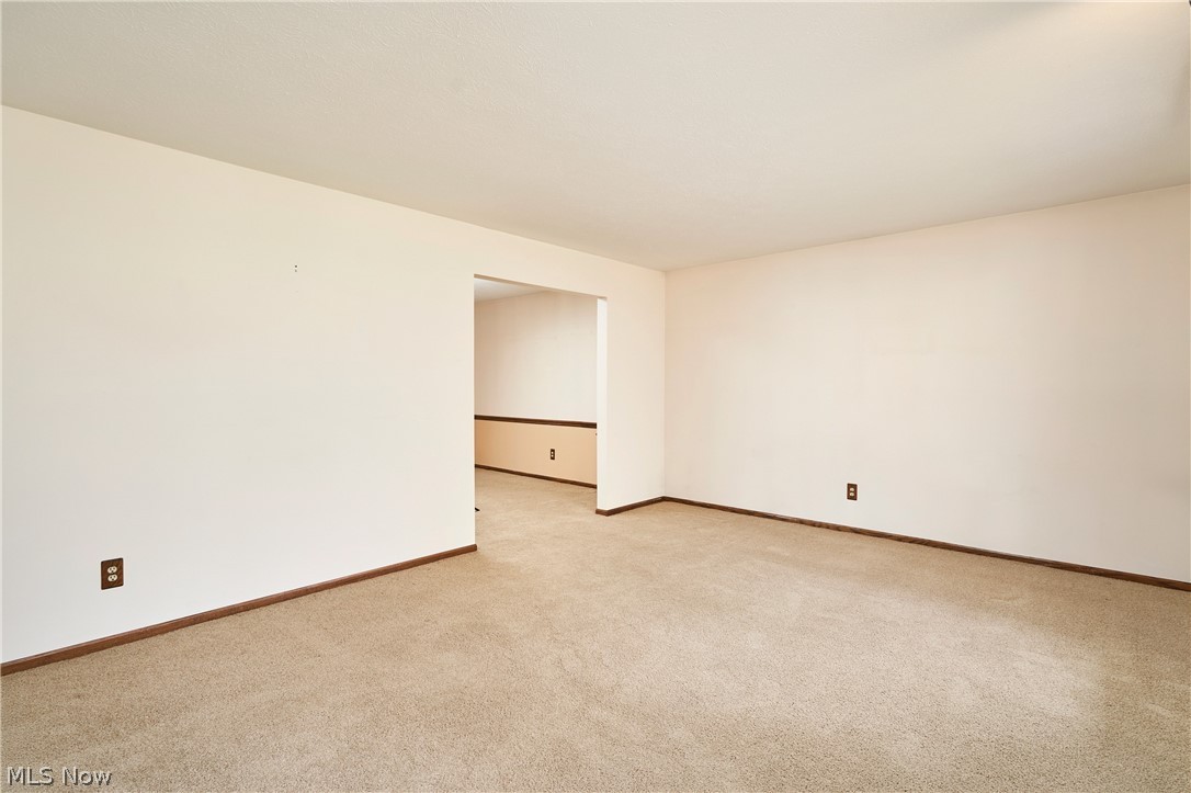 3097 Baughman Road Clinton, OH 44216 - Photo 3 of 27 Carpeted room with light neutral wall tones, wood baseboards, and a doorway leading to an additional space