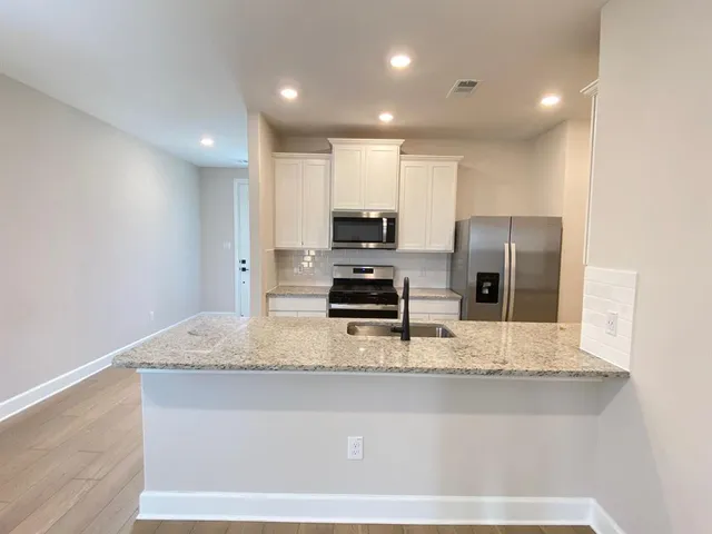 a kitchen with stainless steel appliances granite countertop a sink a stove and a refrigerator