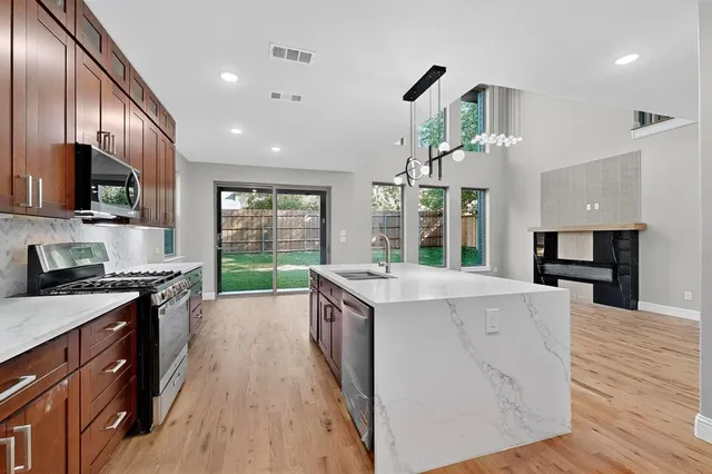 a kitchen with kitchen island granite countertop wooden floors and stainless steel appliances