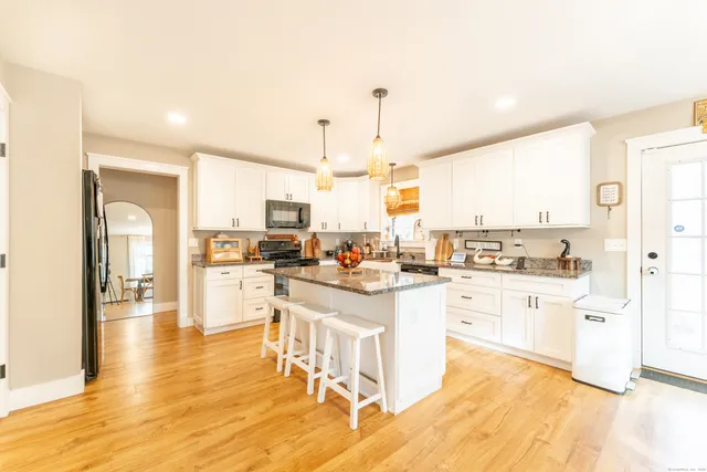 a large white kitchen with lots of counter top space and stainless steel appliances