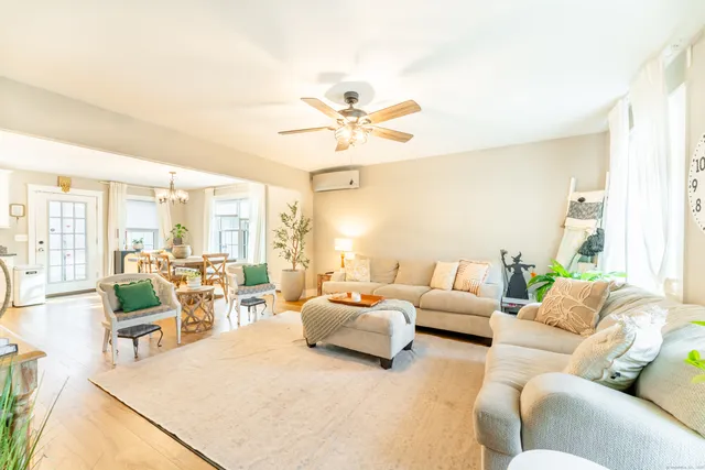 a living room with furniture ceiling fan and a large window