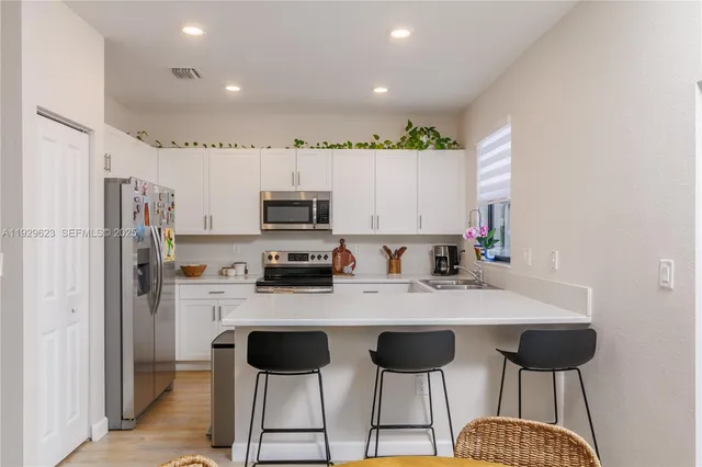 a kitchen with stainless steel appliances kitchen island granite countertop a refrigerator and a stove top oven