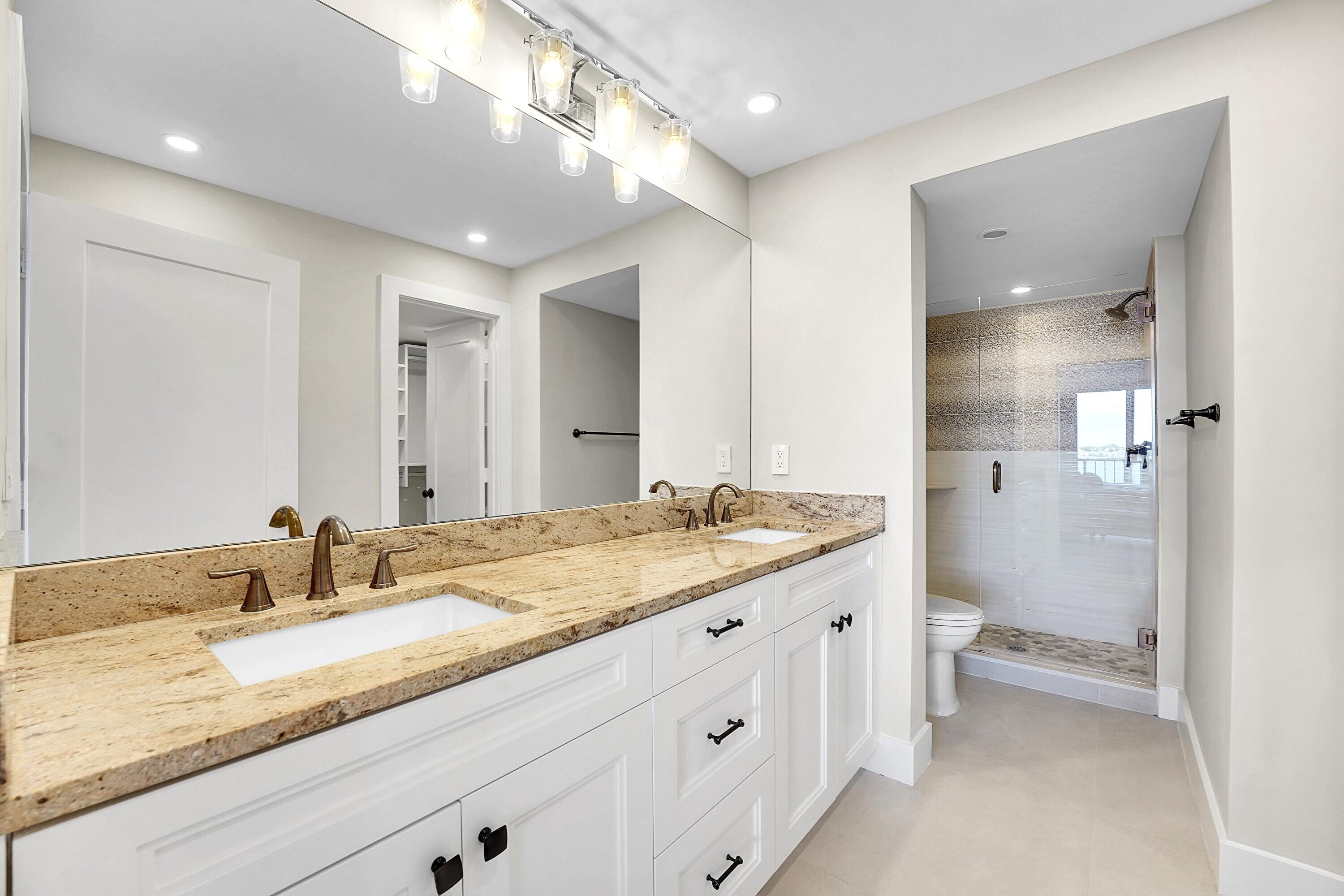 134 Lakeshore Drive, Unit 316 North Palm Beach, FL 33408 - Photo 12 of 30 a bathroom with a granite countertop sink a toilet a large mirror and shower
