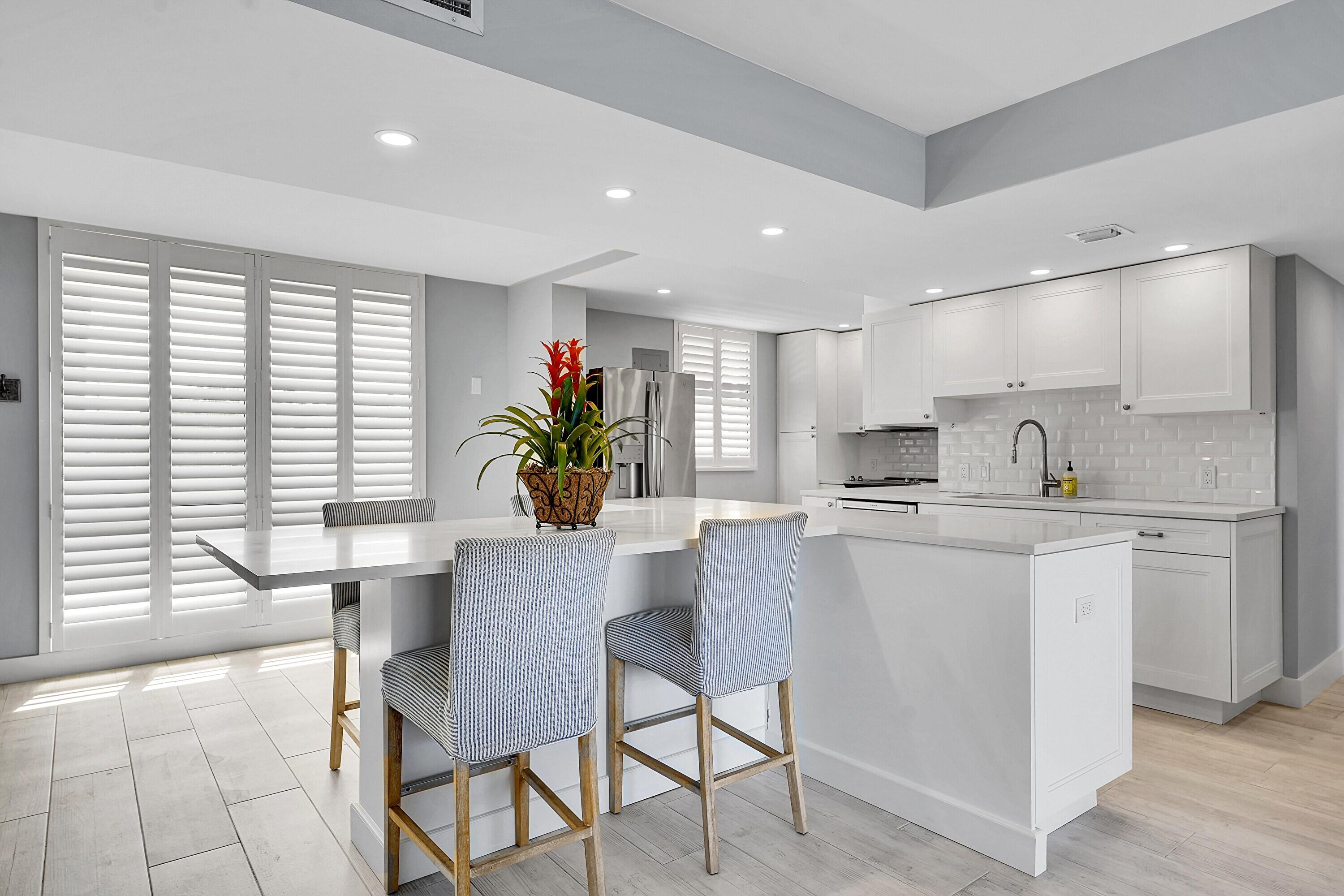 134 Lakeshore Drive, Unit 316 North Palm Beach, FL 33408 - Photo 3 of 30 a kitchen with kitchen island a stove a table and chairs in it