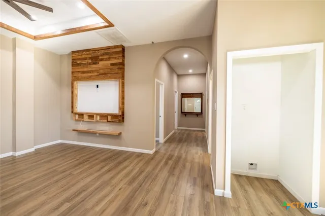 a view of a hallway with wooden floor and a bathroom