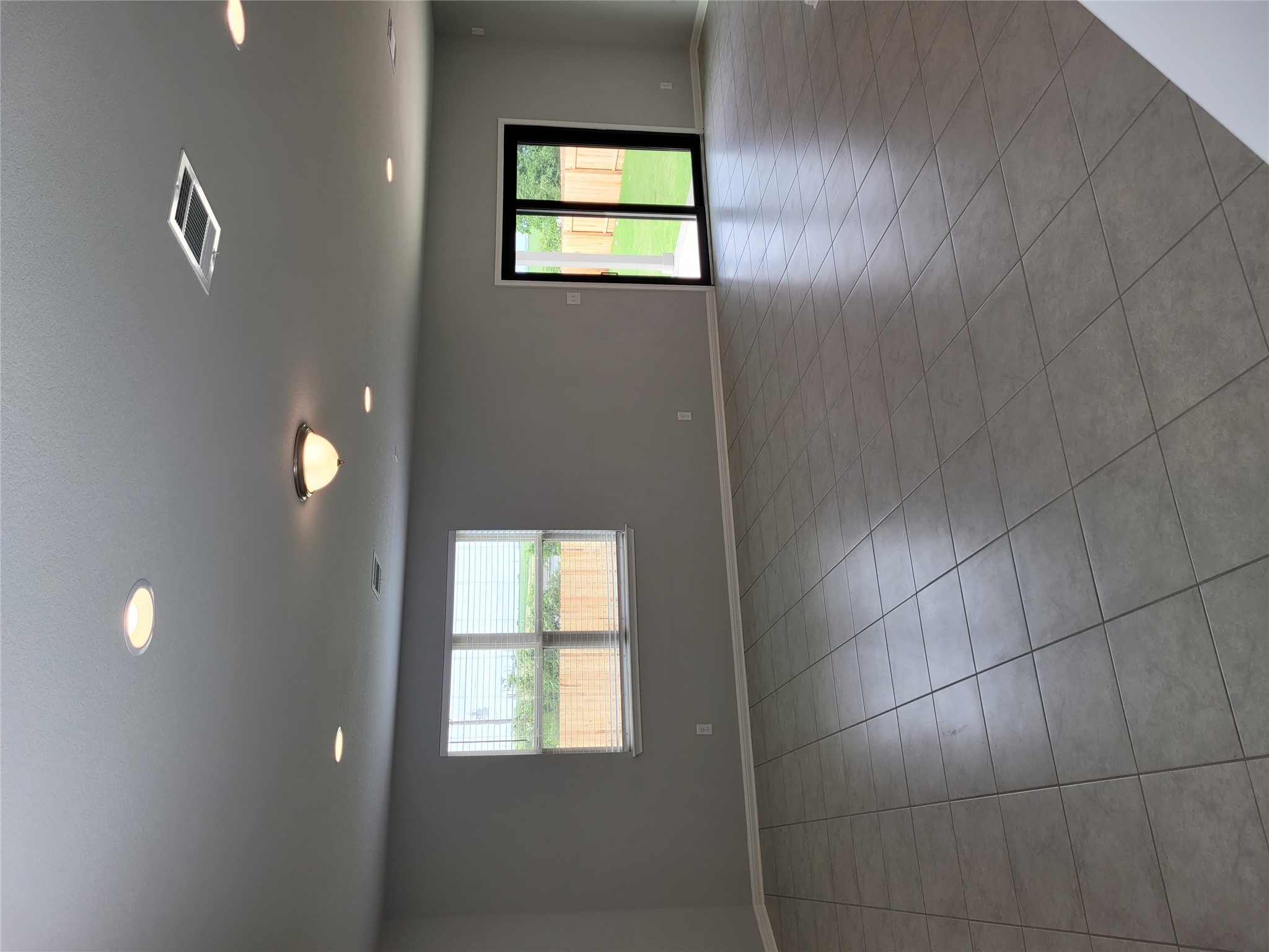 131 Wild Wind Cove Jarrell, TX 76537 - Photo 7 of 26 Spacious interior featuring neutral gray wall paint, large format tile flooring, recessed lighting, and a sliding glass door opening to a fenced yard