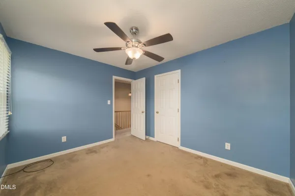 an empty room with a ceiling fan and a window