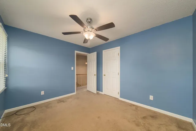 an empty room with a ceiling fan and a window