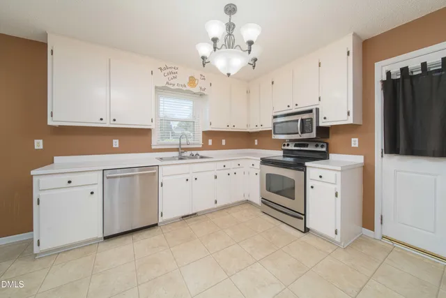 a kitchen with white cabinets white stainless steel appliances and sink