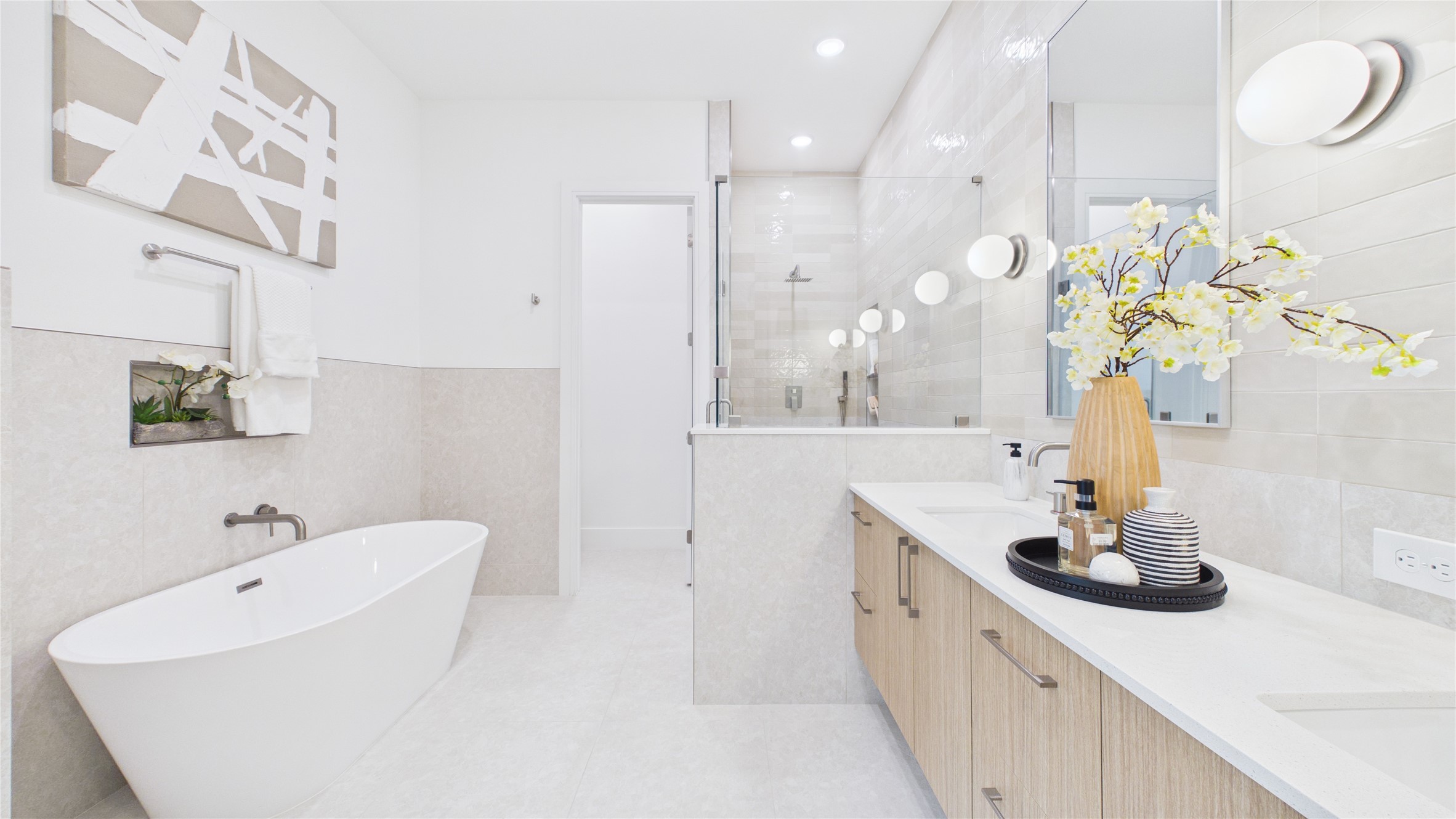 602 Skyland Terrace Way Houston, TX 77009 - Photo 33 of 40 This bathroom features a modern design with a freestanding tub, spacious walk-in shower, and a double vanity. It has sleek, light-colored tiles, ample lighting, and elegant decor accents, creating a bright and luxurious atmosphere.