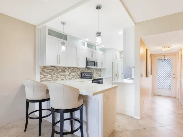 a kitchen with kitchen island a dining table chairs cabinets a sink and a counter top space