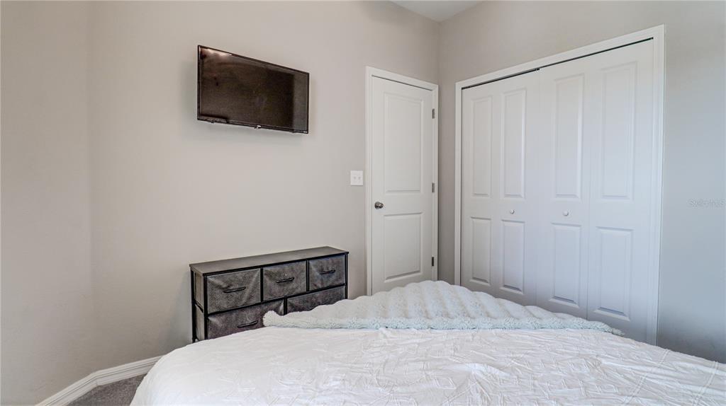 31632 Blue Passing Loop Wesley Chapel, FL 33545 - Photo 36 of 48 a bedroom with a bed and a flat screen tv