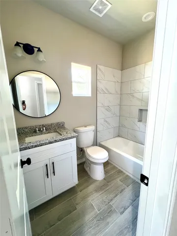 a bathroom with a granite countertop toilet sink and mirror