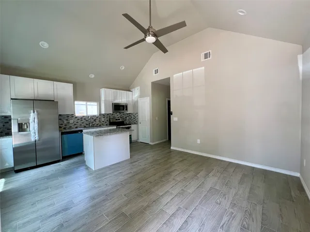 a kitchen with granite countertop a refrigerator and a stove top oven