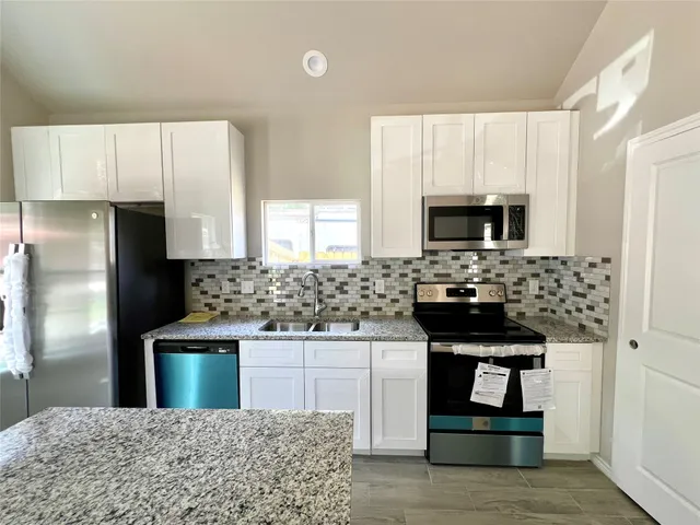a kitchen with kitchen island a sink stainless steel appliances and cabinets