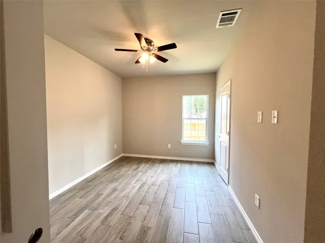 a view of an empty room with wooden floor and a window