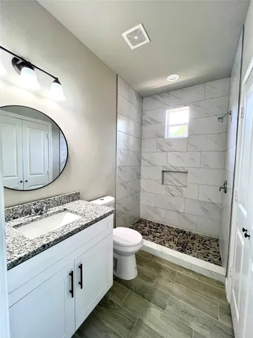 a bathroom with a granite countertop toilet sink and mirror