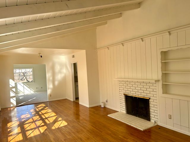 a view of empty room with wooden floor and fireplace