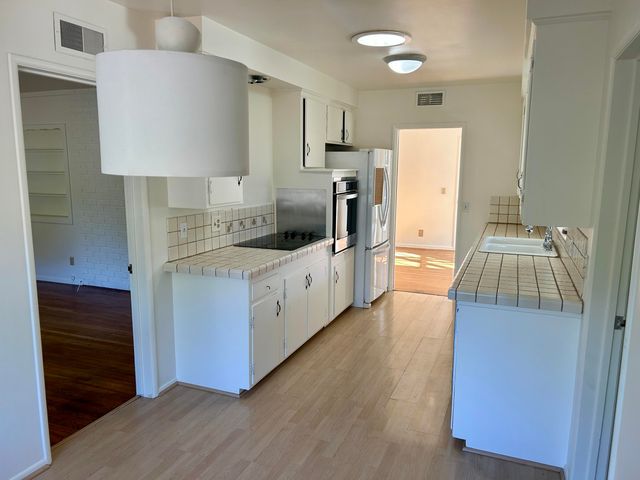 a kitchen with a sink a counter top space stainless steel appliances and cabinets