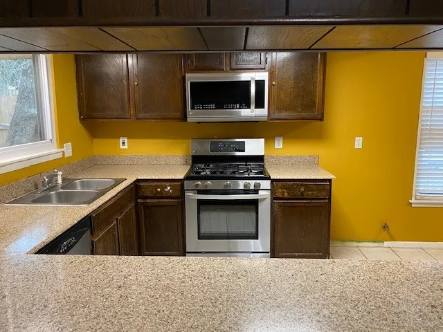 a kitchen with stainless steel appliances granite countertop a sink stove and microwave