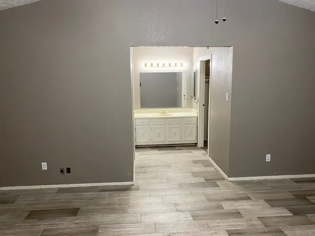 a view of a hallway with wooden floor and a bathroom