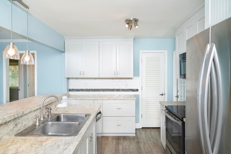 144 Menendez Road St. Augustine, FL 32080 - Photo 11 of 16 Kitchen featuring light countertops, stainless steel appliances, white cabinets, hanging light fixtures, and dark wood finished floors