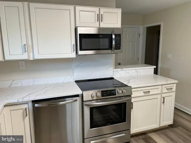 a kitchen with granite countertop white cabinets and stainless steel appliances