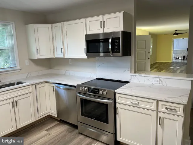a kitchen with granite countertop white cabinets and stainless steel appliances