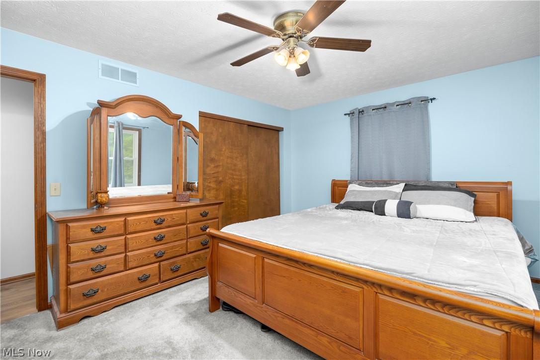 6211 Russia Road Amherst, OH 44001 - Photo 18 of 50 Carpeted bedroom featuring ceiling fan, a closet, and a textured ceiling
