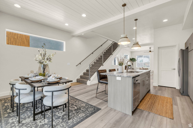 4016 South Burch Way Ogden, UT 84405 - Photo 17 of 30 Open-concept living space with wood-finish flooring, a contemporary kitchen island with a stone countertop, modern pendant lighting, and a staircase with metal railings