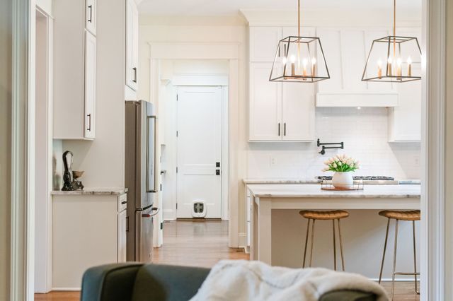 a kitchen with stainless steel appliances granite countertop a stove a sink dishwasher and white cabinets with wooden floor