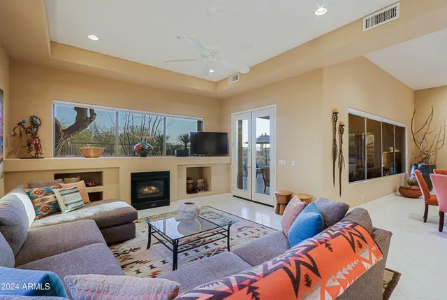 a living room with furniture a flat screen tv and a floor to ceiling window