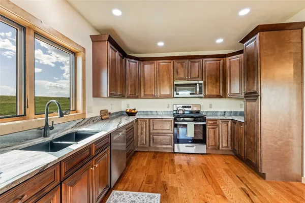a kitchen with kitchen island granite countertop a sink cabinets and stainless steel appliances