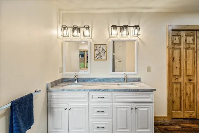 a bathroom with a granite countertop double vanity sink and a mirror