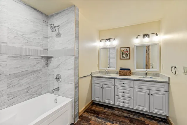 a bathroom with a tub a double vanity sink and mirror