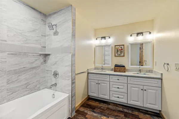 a bathroom with a tub a double vanity sink and mirror