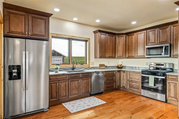 a large kitchen with stainless steel appliances granite countertop a stove a sink dishwasher and a refrigerator