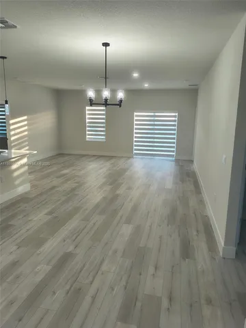 an empty room with wooden floor door and windows